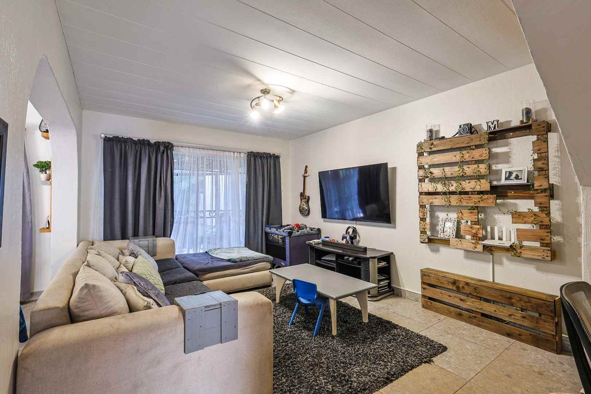 A comfortable living room featuring tiled flooring, a large window with curtain tracks, and a ceiling light fixture.