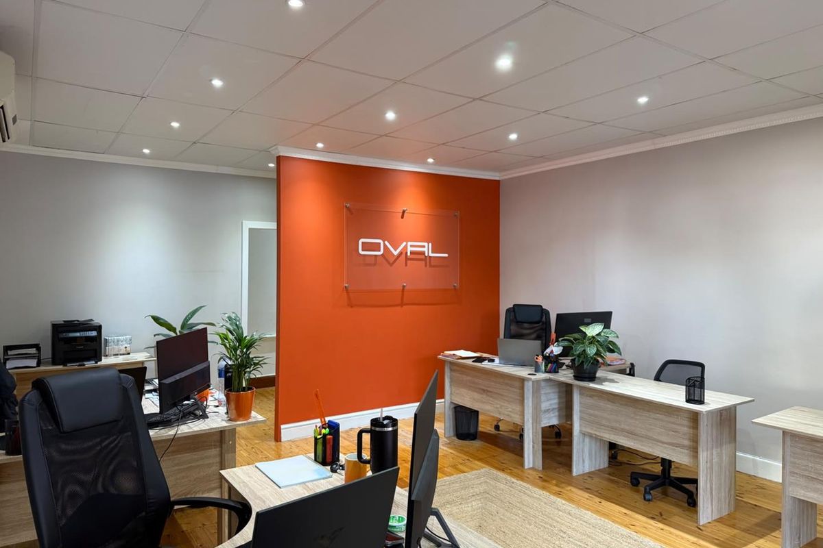 A professional office space featuring timber flooring, recessed downlighting, and a prominent feature wall with corporate branding.