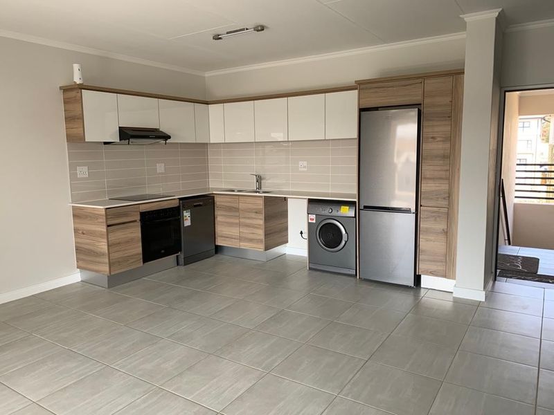 Modern open-plan kitchen featuring sleek two-tone cabinetry, tiled backsplash, integrated appliances, and durable tiled flooring in a clean, well-maintained space.