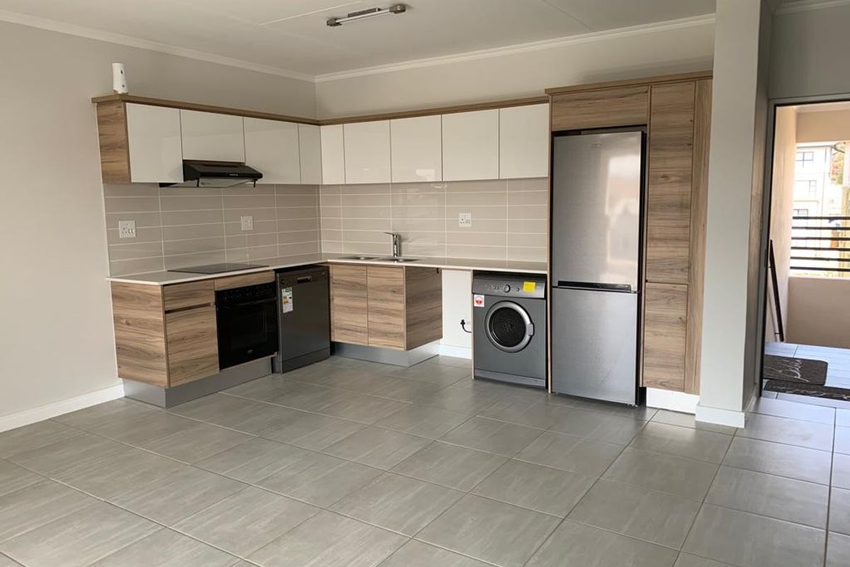 Modern open-plan kitchen featuring sleek two-tone cabinetry, tiled backsplash, integrated appliances, and durable tiled flooring in a clean, well-maintained space.