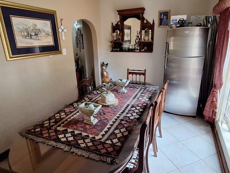 A dining room featuring tiled flooring, an arched doorway leading to adjacent spaces, and a large window providing natural light.