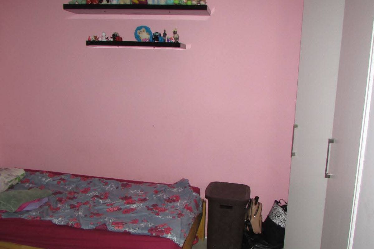 A bedroom featuring pink walls, tiled flooring, and built-in white wardrobe cabinetry.