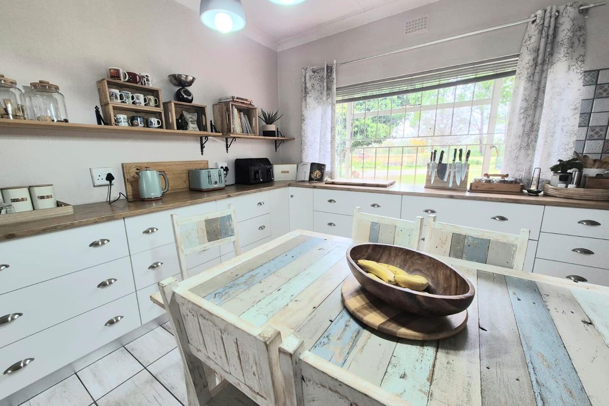 A bright, well-maintained kitchen featuring white cabinetry, wooden countertops, and tiled flooring, offering a clean and functional workspace with ample natural light.