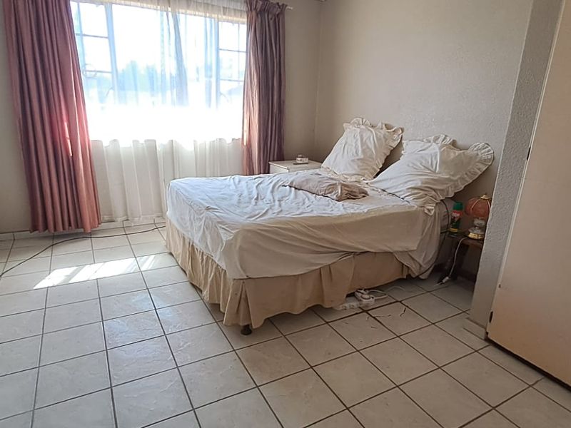 A bedroom featuring tiled flooring and a built-in wardrobe, requiring cosmetic updates to improve the overall aesthetic and condition of the space.
