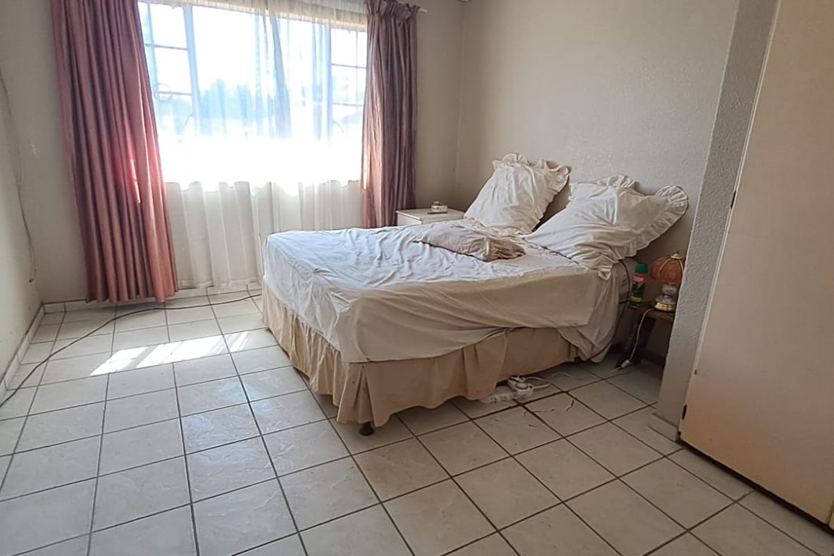 A bedroom featuring tiled flooring and a built-in wardrobe, requiring cosmetic updates to improve the overall aesthetic and condition of the space.