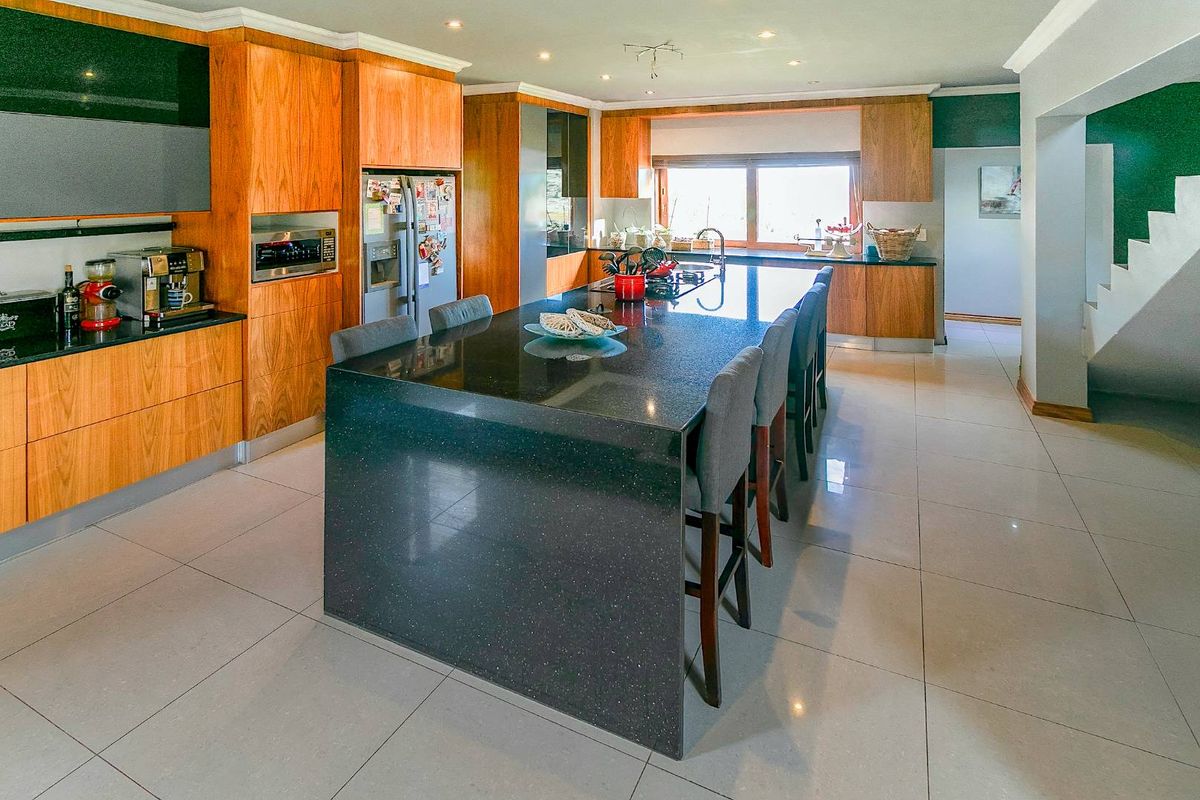 Spacious modern kitchen featuring wood cabinetry, a large central island with a dark stone countertop, and integrated appliances.