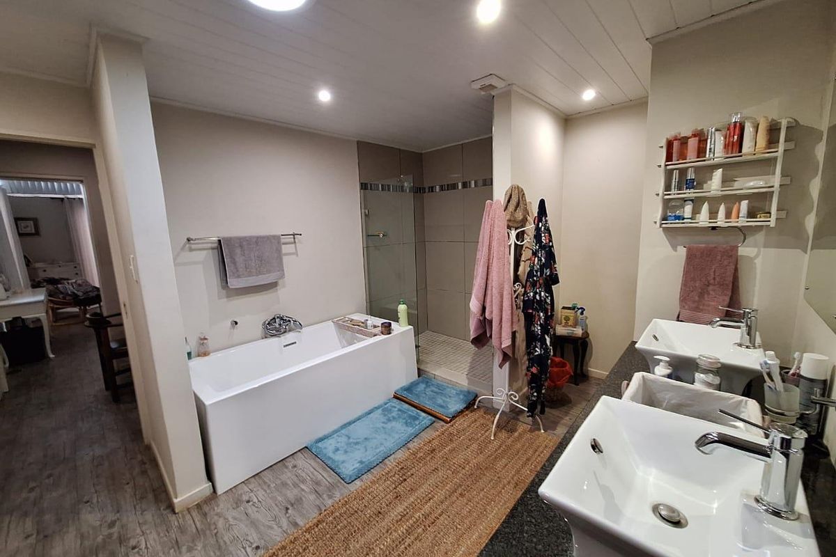A well-appointed bathroom featuring a modern freestanding bathtub, a glass-enclosed walk-in shower, and dual vessel sinks set on a dark granite vanity top.