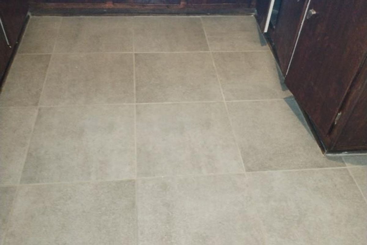 A kitchen area featuring dark wood cabinetry and neutral ceramic floor tiles, presenting a dated aesthetic ready for modernization.