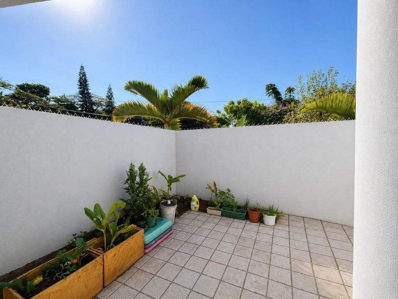 A private outdoor patio area featuring tiled flooring and high perimeter walls with security spikes, offering a blank canvas for outdoor living.