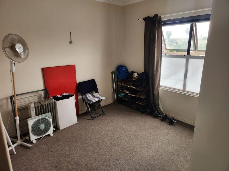 A bedroom featuring carpeted flooring and a top-hung window, currently used as a multi-purpose storage and utility space.