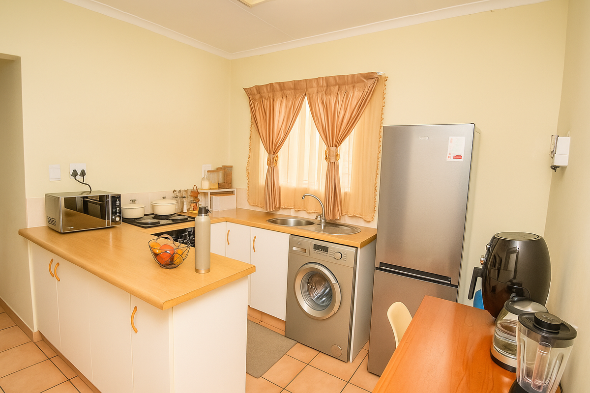 Compact kitchen featuring light-toned cabinetry, laminate countertops, a built-in hob, and integrated space for a washing machine.