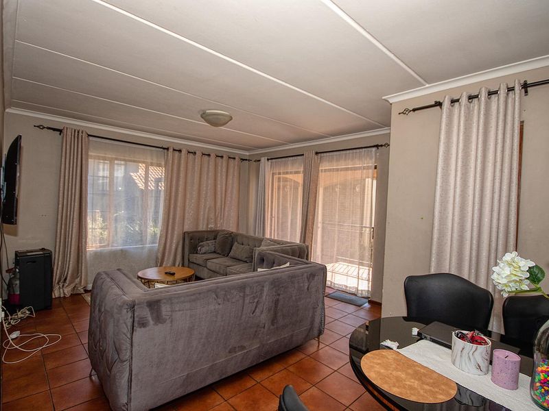 Open plan living and dining area featuring terracotta floor tiles and sliding glass doors leading to an outdoor space.