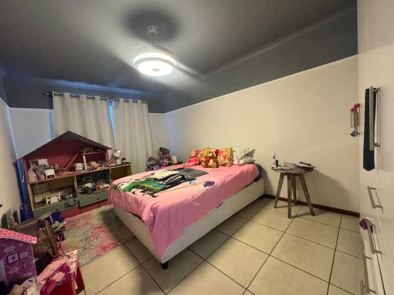 A bedroom featuring tiled flooring, a ceiling fan, and built-in wardrobe storage.