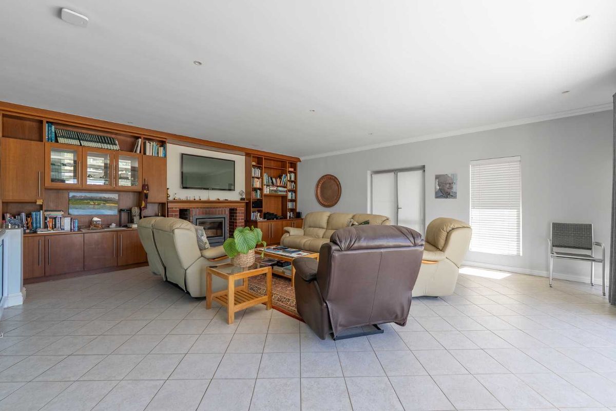 Spacious living room featuring built-in wooden cabinetry, a brick fireplace, and neutral tiled flooring, offering a comfortable and functional family space.