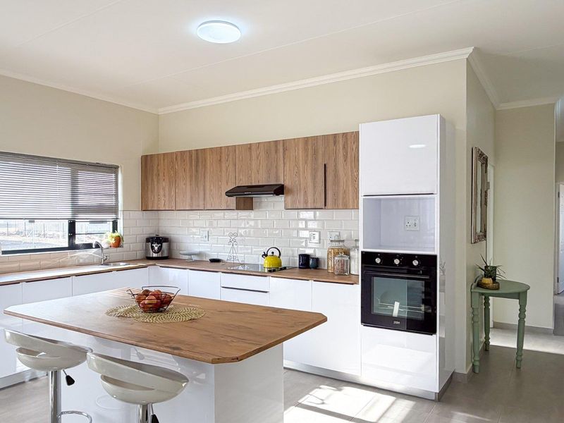 Modern kitchen featuring white and wood-grain cabinetry, subway tile backsplash, integrated oven, and a functional kitchen island with wood-look countertop.