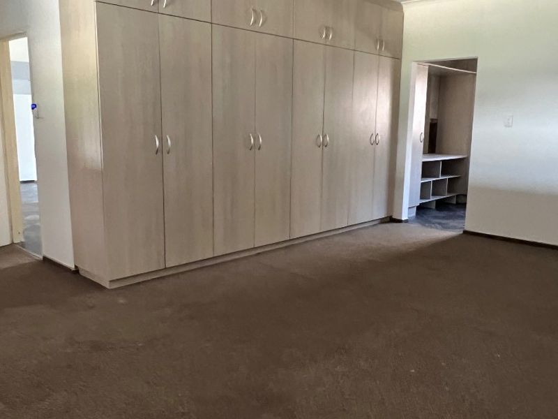 Spacious bedroom featuring extensive built-in cabinetry and an adjoining walk-in closet area, providing ample storage space.
