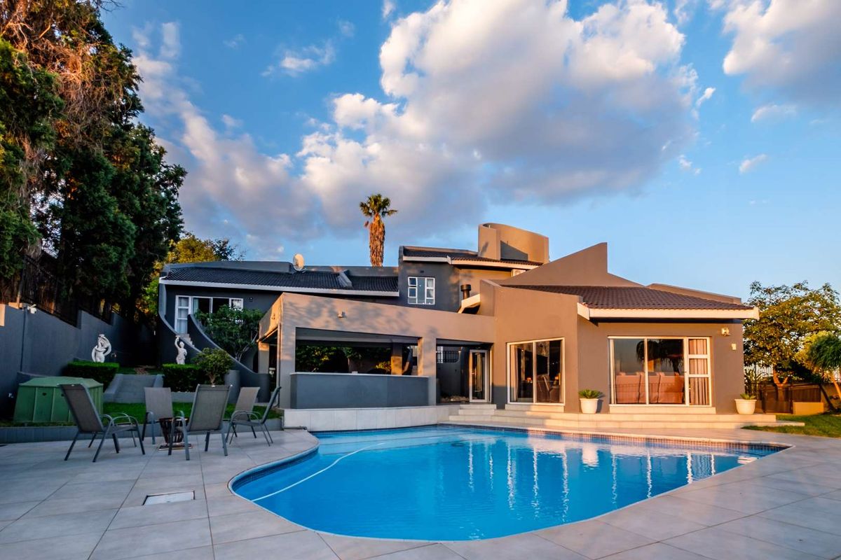 Rear view of the property featuring a modern swimming pool, paved patio area, and covered outdoor entertainment space.