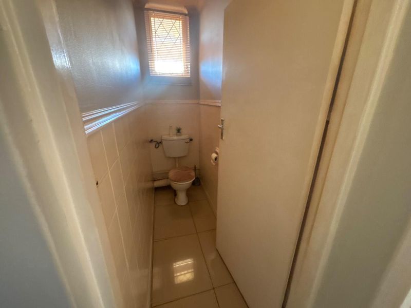 A compact, functional guest bathroom featuring tiled walls, tiled flooring, and a standard toilet fixture.