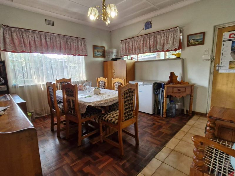 A dining room featuring a combination of parquet and ceramic tile flooring, illuminated by a central chandelier.