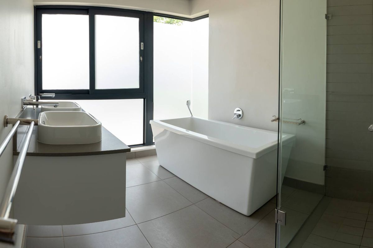 Modern bathroom featuring a freestanding bathtub, double vanity with vessel sinks, and a glass-enclosed shower with contemporary fixtures.