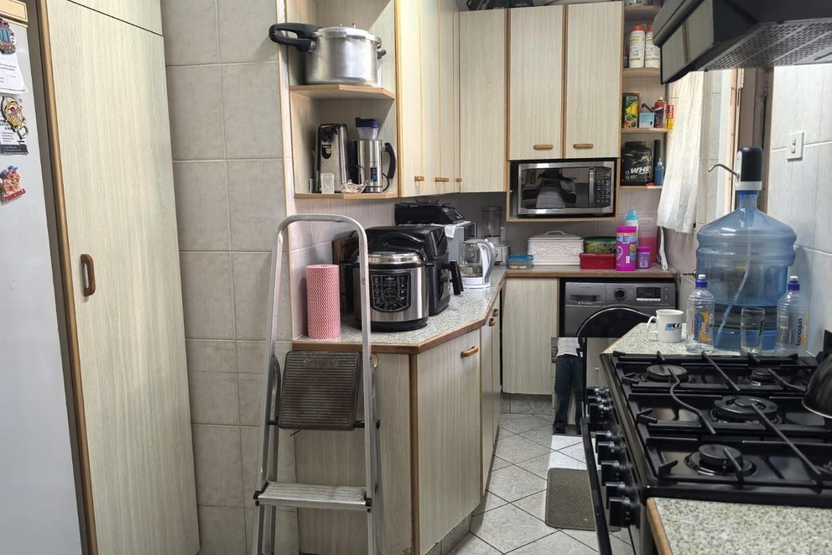 Compact kitchen featuring laminate cabinetry, gas hob, extractor fan, and integrated laundry facilities with tiled flooring and backsplash.