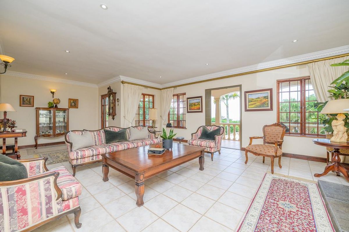 Spacious living room featuring tiled flooring, recessed lighting, crown molding, and direct access to an outdoor patio area through a doorway.