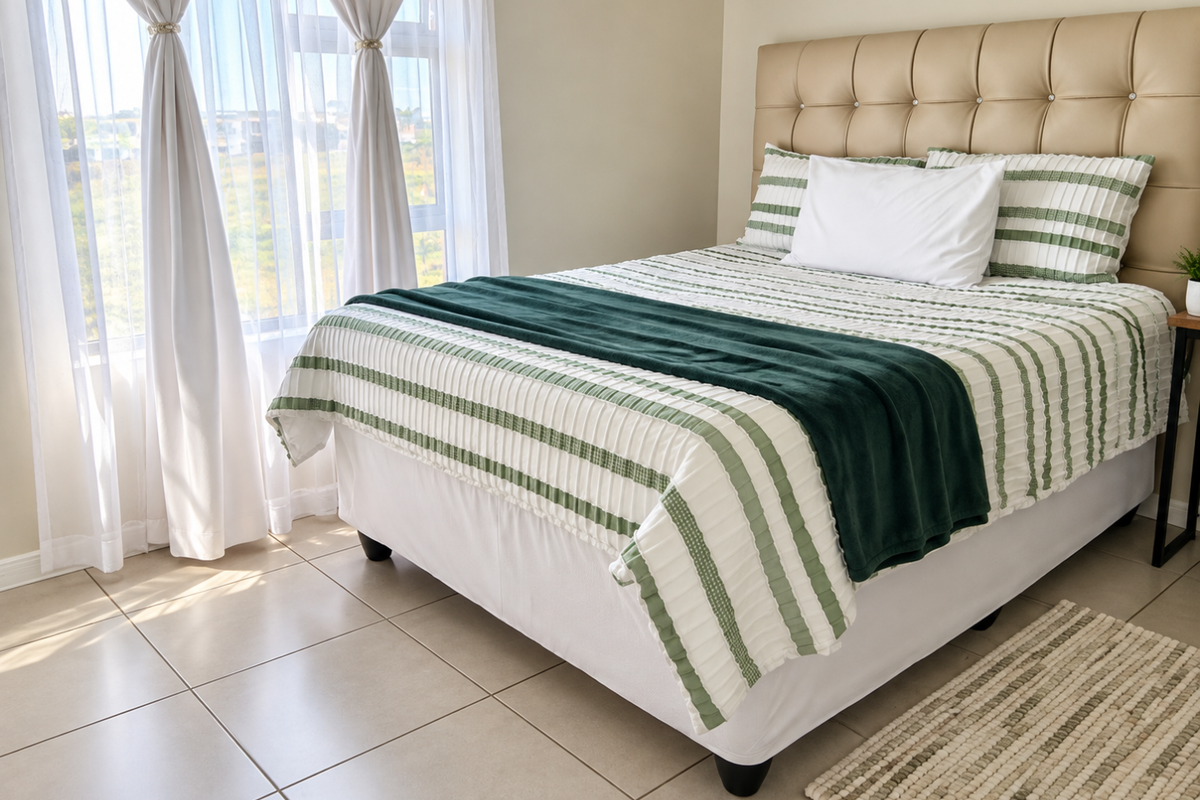 A bright and well-maintained bedroom featuring neutral tiled flooring and a large window that allows for ample natural light.
