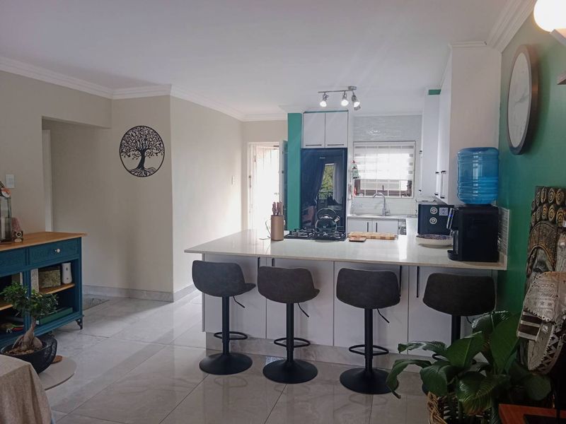 An open-plan kitchen featuring a central island with a stone countertop, gas hob, and modern cabinetry, seamlessly integrated with the living area.