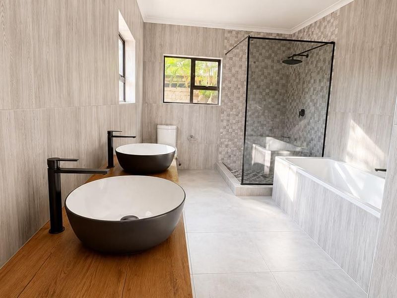 Modern bathroom featuring a double vanity with vessel sinks, a walk-in shower with a glass enclosure, and a built-in bathtub with contemporary finishes.