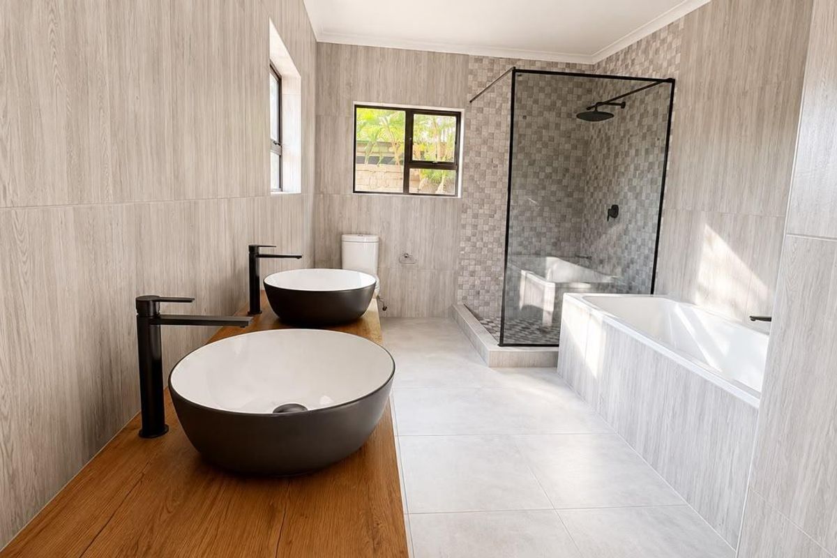 Modern bathroom featuring a double vanity with vessel sinks, a walk-in shower with a glass enclosure, and a built-in bathtub with contemporary finishes.