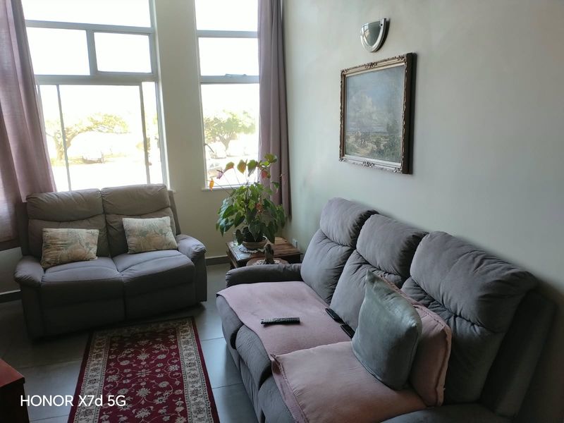 A bright living room featuring large windows that provide ample natural light and tiled flooring throughout.
