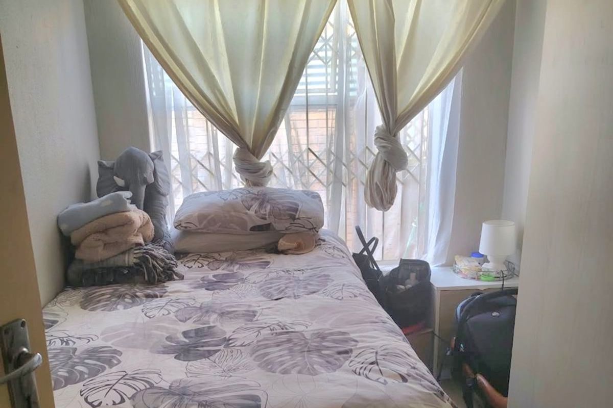 A compact bedroom featuring a window with a fitted security gate, providing natural light and essential security.