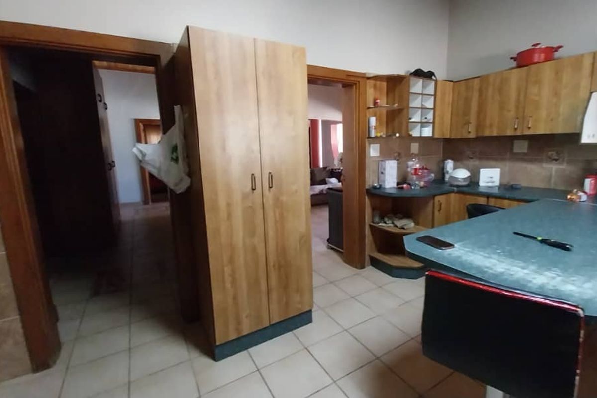 A functional kitchen featuring wood-look cabinetry, tiled flooring, and a breakfast bar, providing a practical layout with direct access to adjacent living areas.