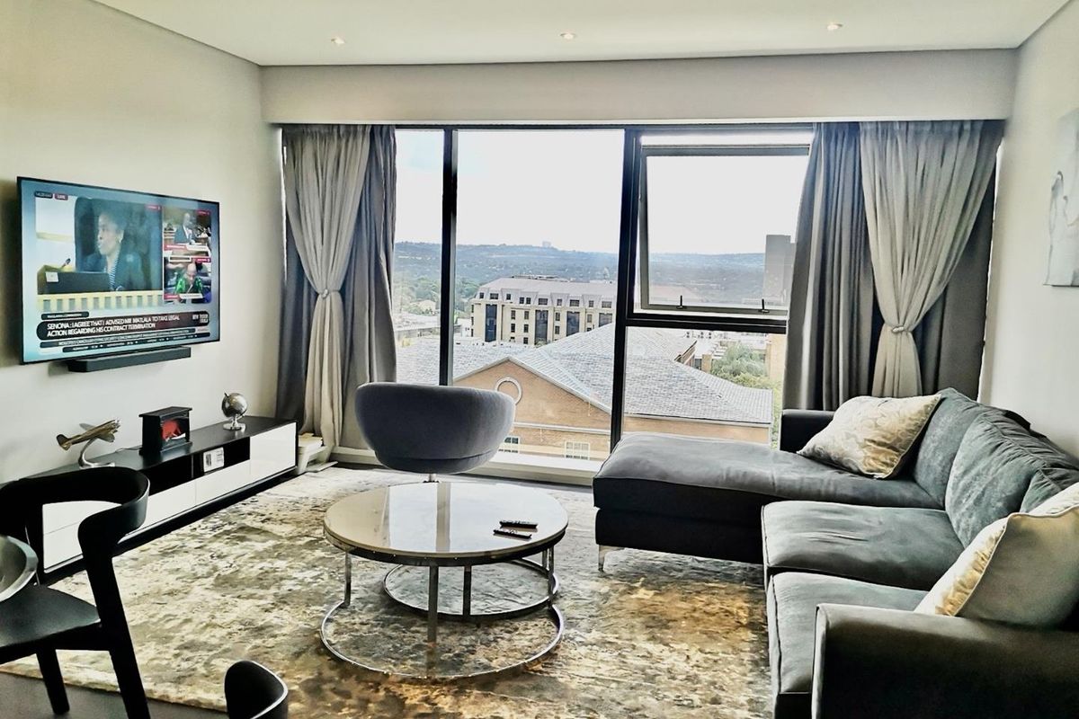 Modern living room featuring large floor-to-ceiling windows with expansive urban views and recessed downlighting.