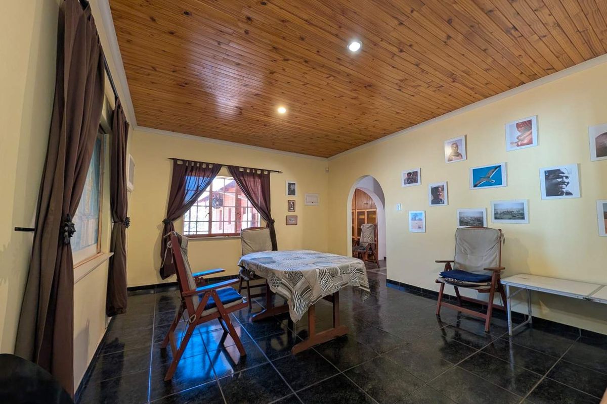 A living area featuring a warm timber tongue and groove ceiling, dark ceramic floor tiles, and a classic arched doorway leading to adjacent spaces.