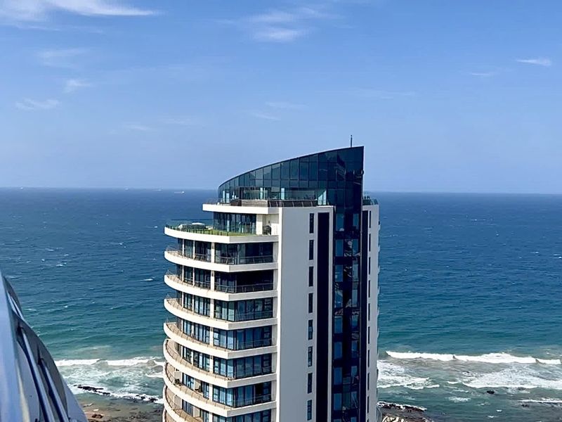 A high-angle exterior view showcasing a modern coastal apartment building overlooking the ocean.