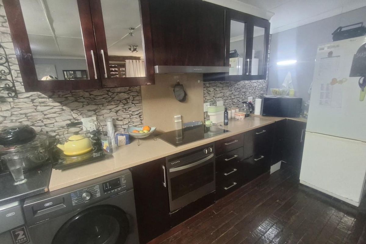 A functional kitchen featuring dark wood cabinetry, a built-in oven with an electric hob, and a stone-look backsplash.