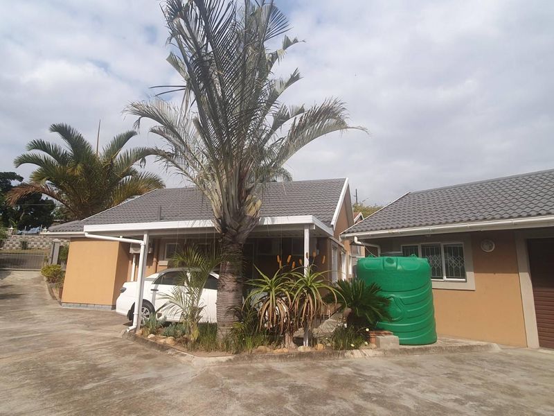 Front view of a residential property featuring a tiled roof, concrete driveway, garage, and a water storage tank.