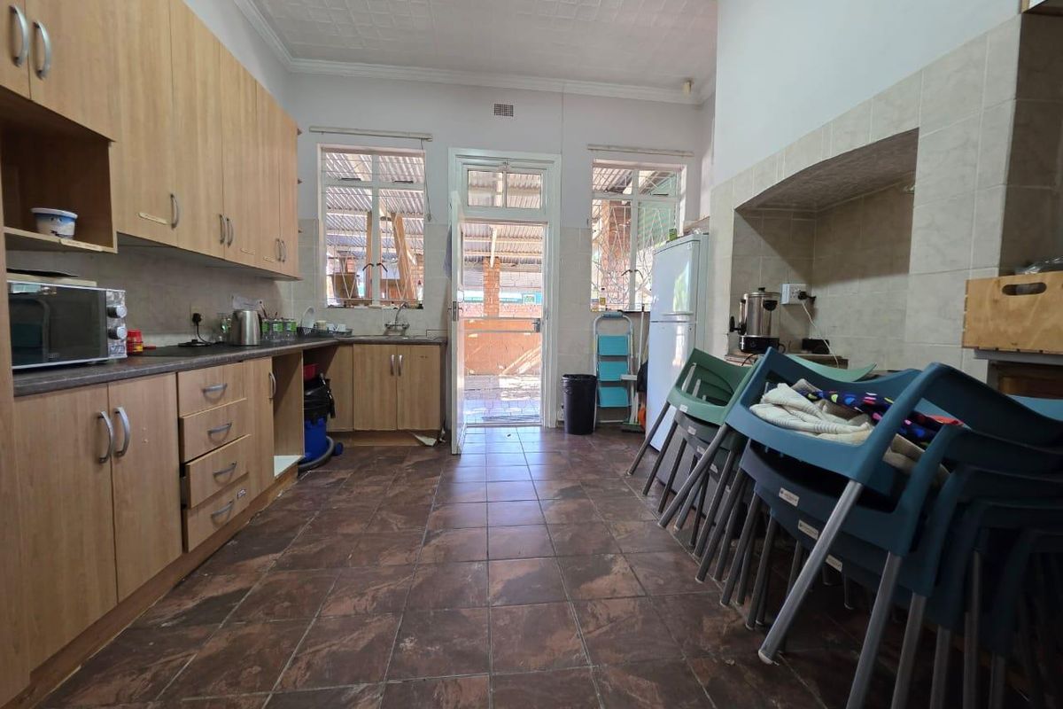 A functional kitchen featuring wood-look cabinetry, tiled flooring, and direct access to an outdoor area through a rear door.
