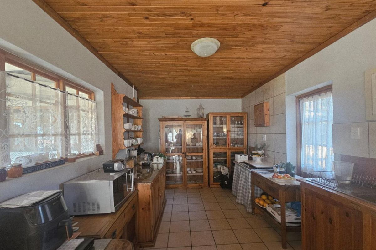 A rustic kitchen featuring timber cabinetry, tiled flooring, and a wood-paneled ceiling, offering a traditional aesthetic with ample storage space.