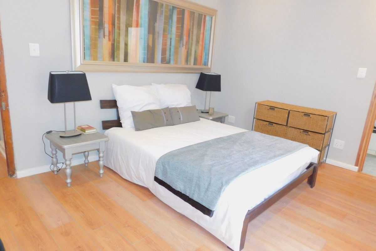 A well-maintained bedroom featuring light-toned laminate flooring and neutral wall finishes, providing a clean and functional living space.