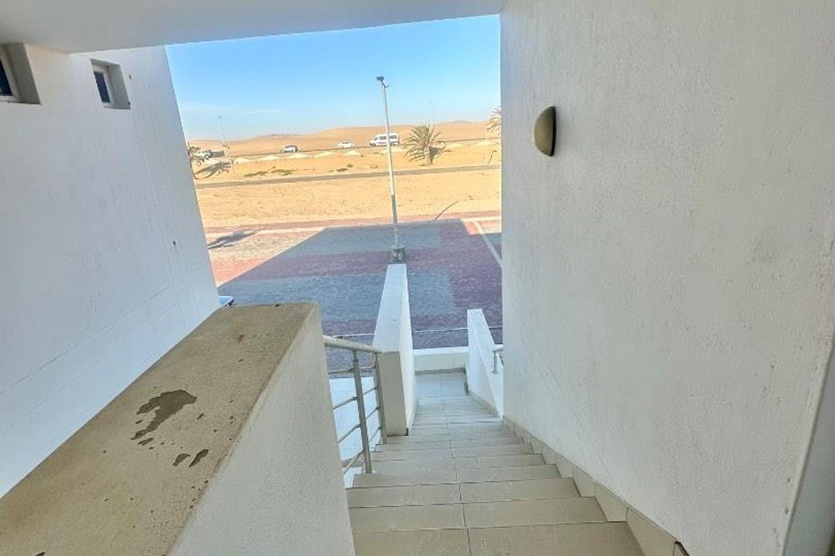 Exterior staircase leading down to a paved area with desert landscape views, featuring concrete balustrades and tiled steps.