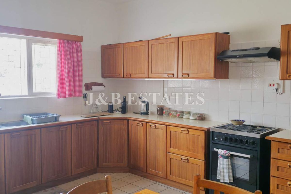 A functional kitchen featuring traditional timber cabinetry, tiled splashbacks, a double basin sink, and a freestanding gas stove with an extractor fan.