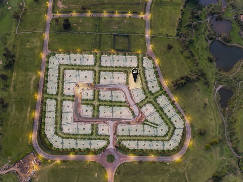 Aerial view of a residential estate development featuring numbered plots, paved internal roads, and street lighting, situated within a landscaped golf course environment.