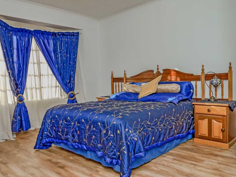 A bedroom featuring laminate flooring and a bay window, providing a functional and well-lit sleeping space.