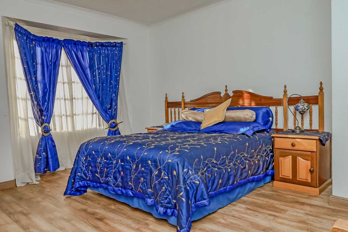 A bedroom featuring laminate flooring and a bay window, providing a functional and well-lit sleeping space.
