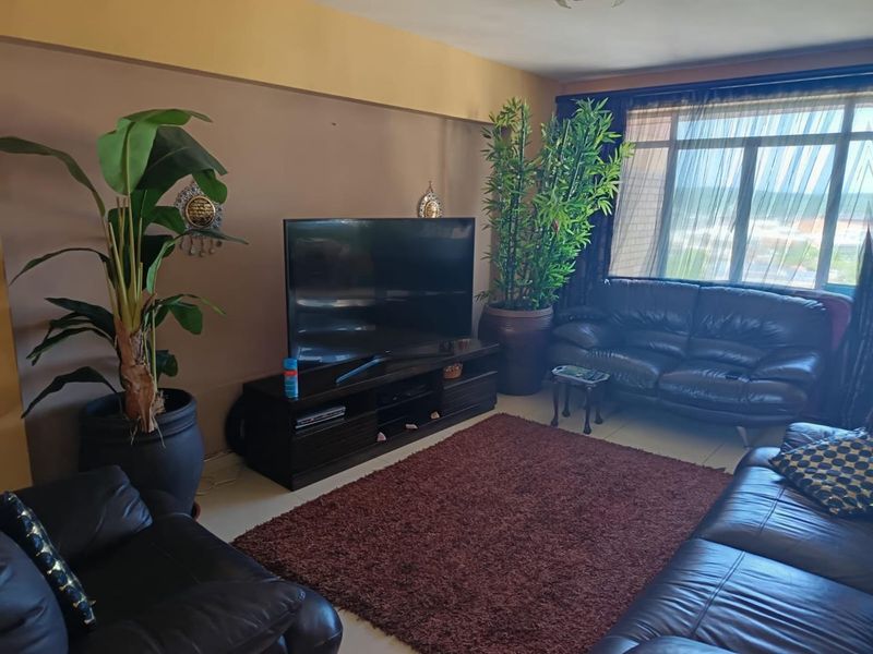 A comfortable living room featuring large windows that provide natural light and tiled flooring throughout the space.