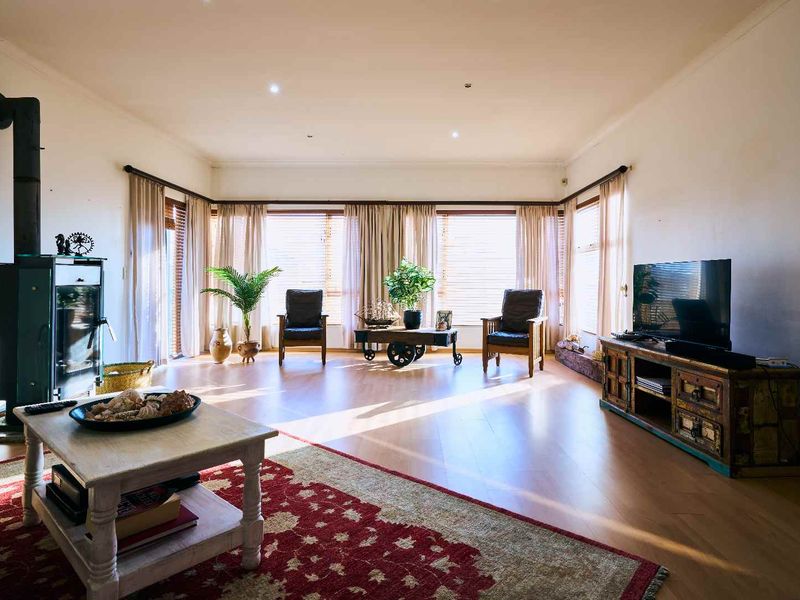 Spacious living room featuring laminate flooring, a wood-burning stove, and large windows that provide ample natural light.