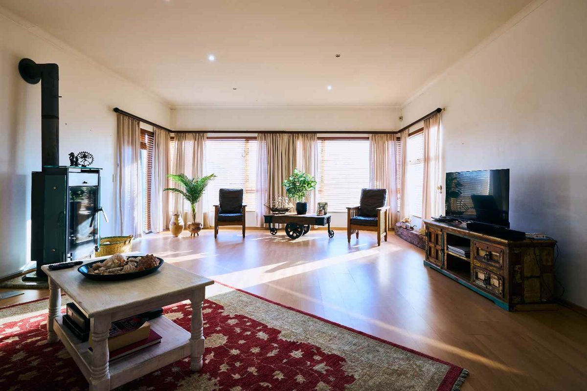 Spacious living room featuring laminate flooring, a wood-burning stove, and large windows that provide ample natural light.