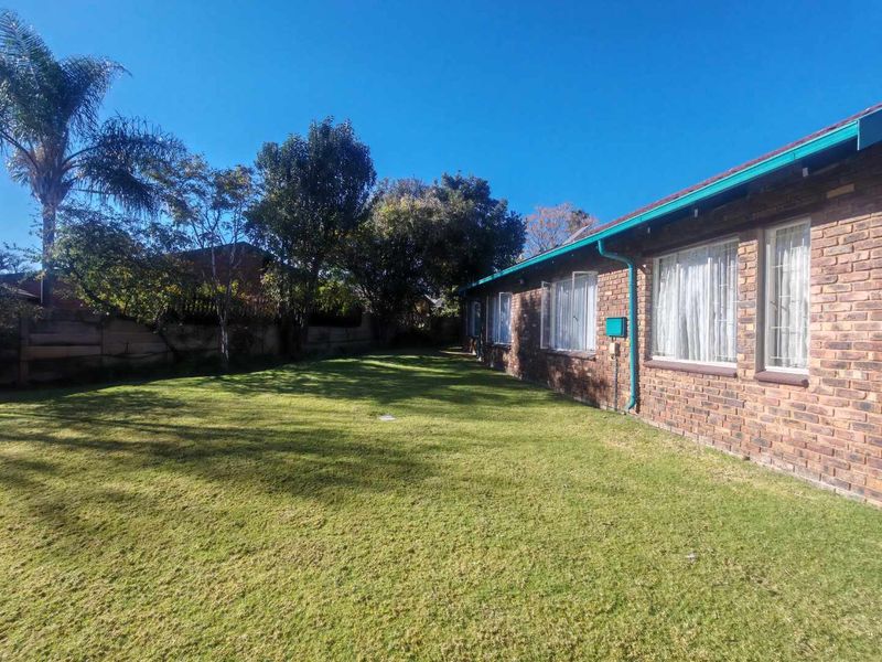A view of the rear garden featuring a face brick exterior wall, established lawn, and boundary wall.